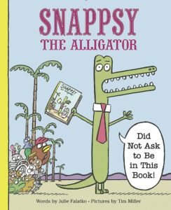 Cover image of the picture book Snappsy the Alligator Did Not Ask to Be In This book, an aggrieved alligator holding a copy of the same book with a chicken looking on. 