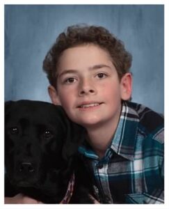 School photo of a boy with a black dog.